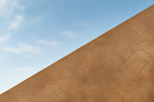 A bold diagonal line divides a soft sky from a textured earth tone surface.