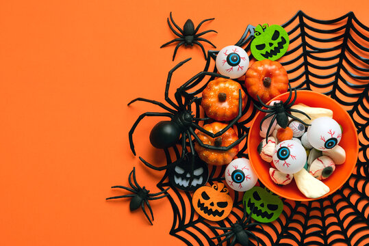 Top view of plate with Halloween candy,spiders,Halloween pumpkins and spider web with copy space for text. Halloween concept background