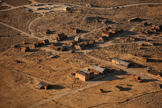 Aerial view of the historic ghost town of Bodie, featuring weathered wooden buildings and dusty streets in the high desert landscape of Mono County, California, United States.