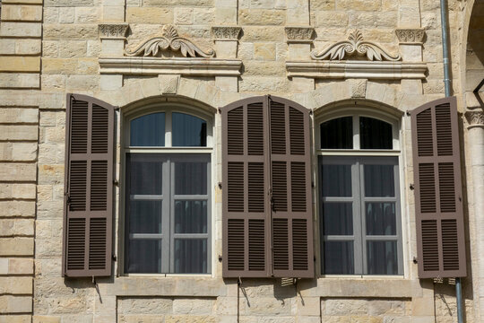 Two arched windows with wooden shutters are set into an ornately carved sandstone facade, Beqaa Governorate, Zahle, Lebanon