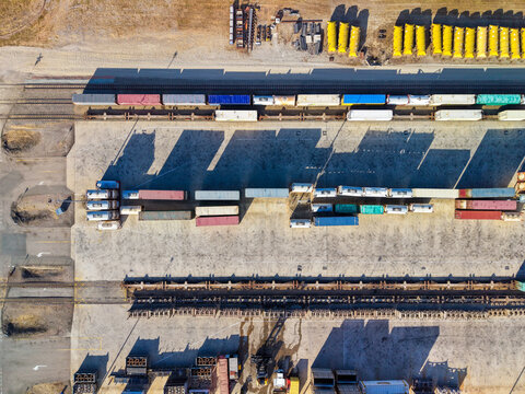 Aerial view of TGE Terminal featuring rows of colorful shipping containers, freight train cars on tracks, and industrial infrastructure in Stuart, Queensland, Australia.