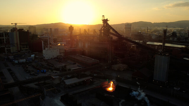 Aerial view of the steel works in Linz featuring a blast furnace and glowing molten slag during sunset in Linz, Upper Austria, Austria.