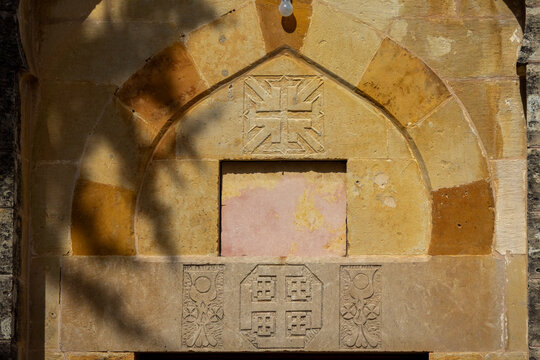 A carved stone archway features a decorative cross and heraldic emblems above an empty marble panel, Mount Lebanon Governorate, Deir el Qamar, Lebanon