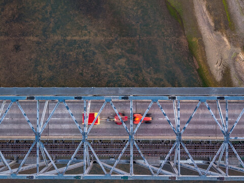 Aerial view of the Burdekin River Bridge with a tractor and trailer crossing the steel truss structure over the riverbed in Home Hill, Queensland, Australia.