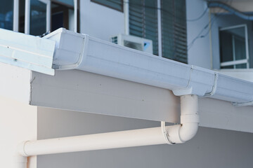 White plastic rain gutter system installed on building roof. © Aphisith