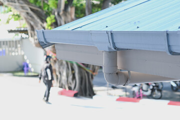 White plastic rain gutter system installed on building roof. © Aphisith