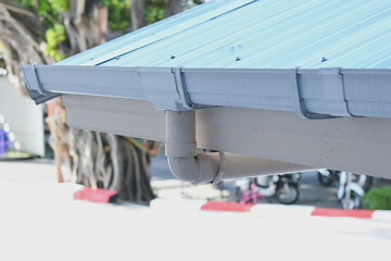 White plastic rain gutter system installed on building roof. © Aphisith