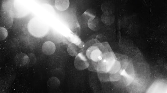 Abstract black and white background with bright glowing light flares and soft out of focus bokeh circles