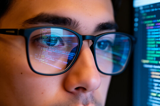 Coder wears glasses working on computer looking at programming code