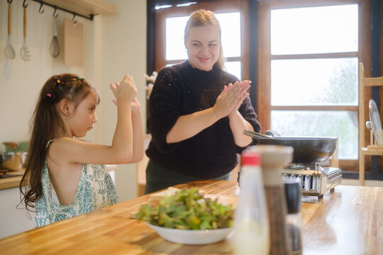Woman and young girl celebrating after cooking a meal together at home.