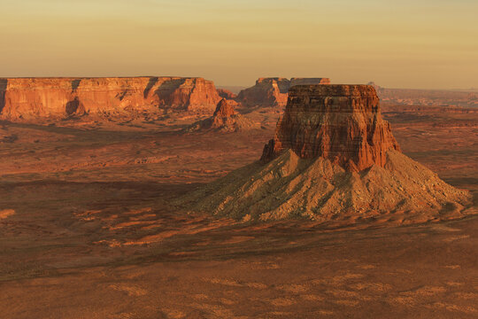 Aerial view of Lake Powell landscape featuring dramatic red rock mesas, rugged desert terrain, and golden hour light in Page, Arizona, United States.