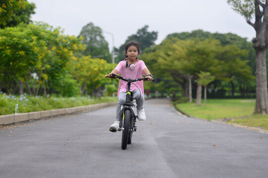 A girl is riding a bicycle in the park on a holiday.