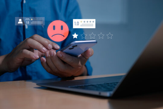 Customer feedback and low rating concept showing person reviewing service on smartphone with an unhappy emoji and one-star ratings, highlighting dissatisfaction, reviews, service quality