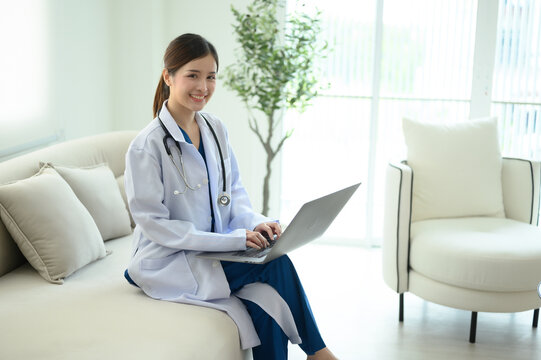 A female doctor is sitting and working at the clinic while waiting to examine patients.
