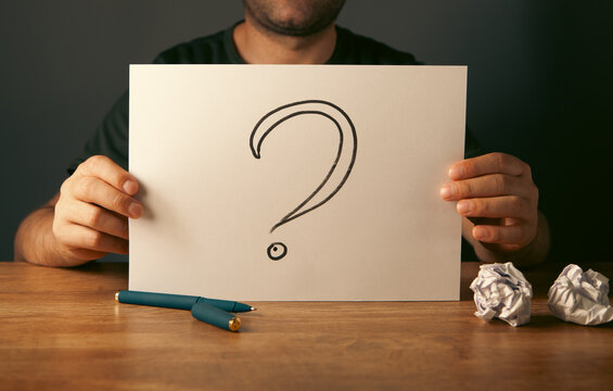 Man holding a paper with question mark and crumpled paper.