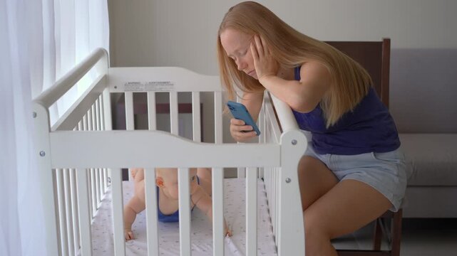Exhausted mother sitting beside crib with three-month-old baby boy, staring at phone.