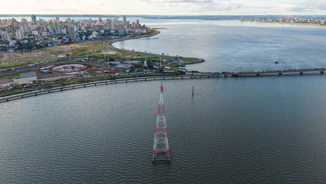 Aerial view of the San Roque Gonzalez de Santa Cruz bridge over the Parana River with a transmission tower and the city skyline of Posadas, Misiones Province, Argentina.