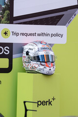 Obraz premium NEW YORK, USA – SEPTEMBER 16, 2026: a Formula One racing helmet display with sponsor logos on a bright green promotional backdrop.
