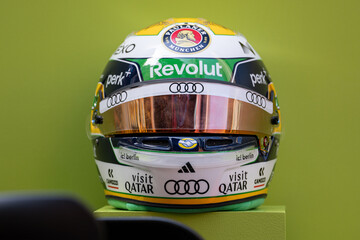 Fototapeta premium NEW YORK, USA – SEPTEMBER 16, 2026: a Formula One racing helmet on a pedestal with sponsor logos and a green background.