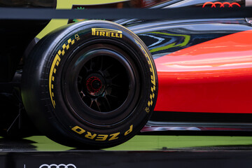 Obraz premium NEW YORK, USA – SEPTEMBER 16, 2026: a Formula 1 race car wheel with Pirelli tire and glossy red black bodywork in close-up.