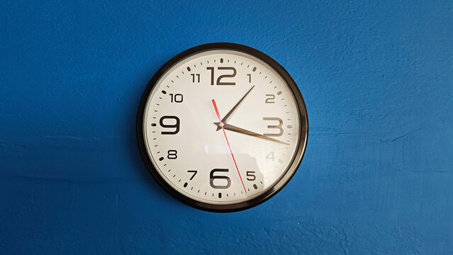 Wall clock with black frame and white face indicating 3,10, symbolizing time management and deadlines