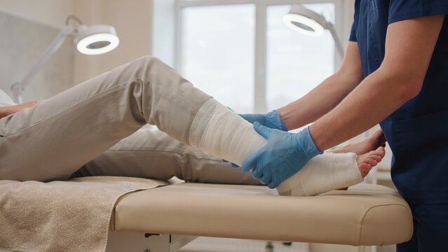 Doctor examining a patient's bandaged leg on an exam table