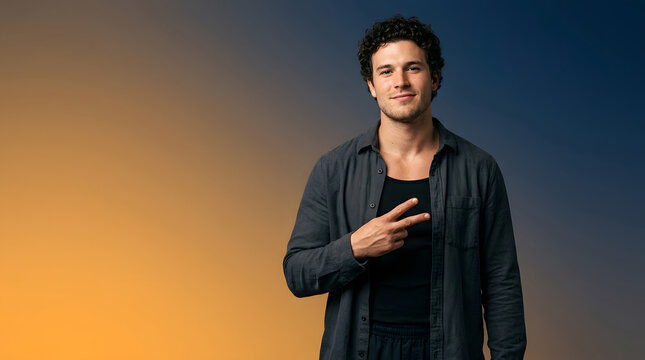 Young smiling man, showing peace sign gesture and looking at camera, casual dark grey shirt over black tank top, warm yellow and blue gradient studio backdrop, social media and marketing campaigns.