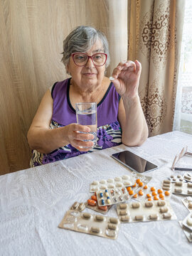 Senior Woman Choosing Daily Pill Beside Multiple Medication Packs at Home