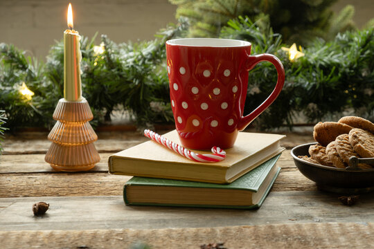 Red polka dotted mug and cookies on wooden table decorated for Christmas. Festive tea party of coffee time. Cozy Xmas mood