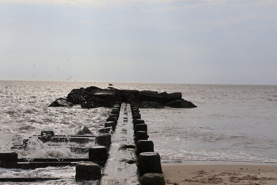 An old wood and stone jetty sitting in the calm wake of the North Cape May Bay on a summer evening.