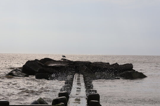 An old wood and stone jetty sitting in the calm wake of the North Cape May Bay on a summer evening.