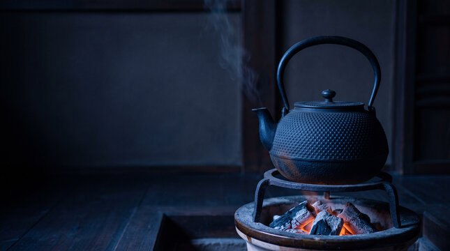 Cast iron kettle steaming on a trivet over charcoal at night