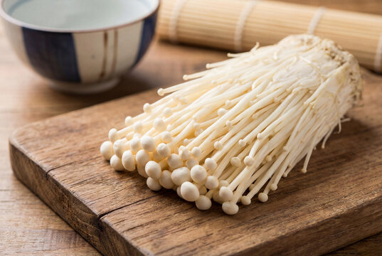 Delicate enoki mushrooms on a wooden table. Rustic style, natural light