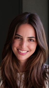 Closeup of a smiling beautiful young brunette woman with long hair looking at the camera and then turning her face towards the sun, feeling happy and enjoying the warm sunlight on her skin