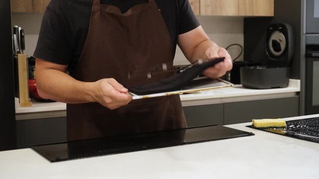 Careful man dismantling a dirty kitchen extractor hood filter for cleaning and maintenance