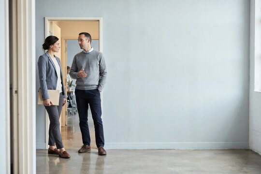 Brief corridor catch up between colleagues beside a glass walled meeting room