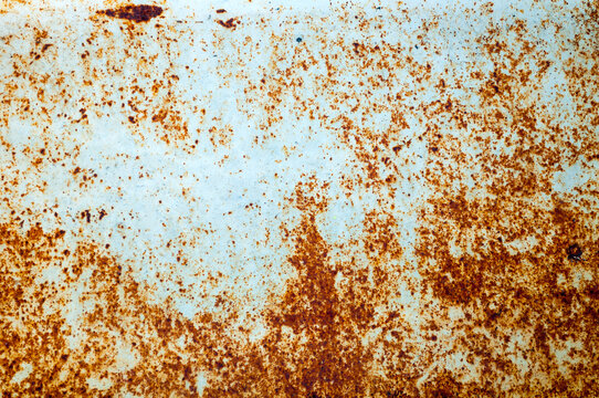 Texture background. A white metal surface covered with brown rust spots. Speckled corrosion patterns and worn paint across the aged industrial panel