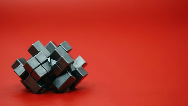 A sophisticated cluster of metallic cubes arranged in a complex geometric formation against a minimalist deep red background