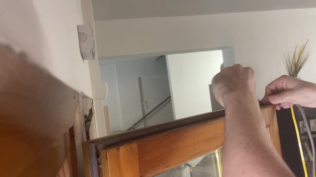 Man hand applying self adhesive weather stripping seal tape on wooden window frame for home insulation. High quality 4k footage