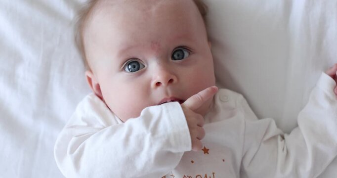 Cute little baby on bed at home, top view. Camera spinning and moving backwards