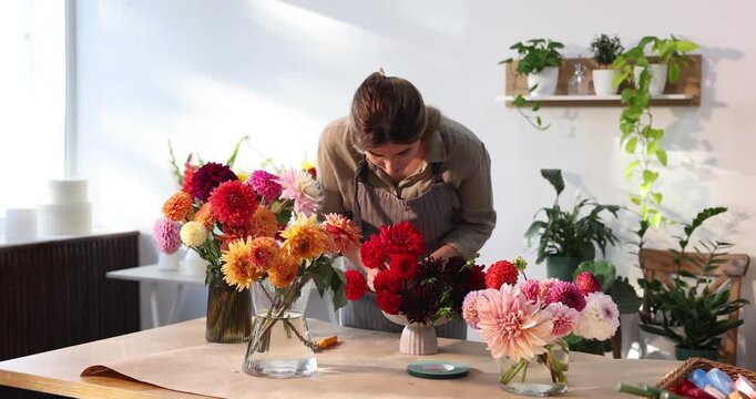 Florist making floral composition with dahlia flowers at table in shop