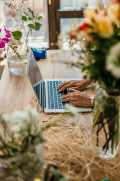 Florist hands typing on laptop in flower shop