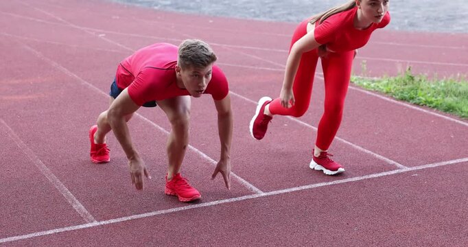Athletes getting into start position and running at stadium