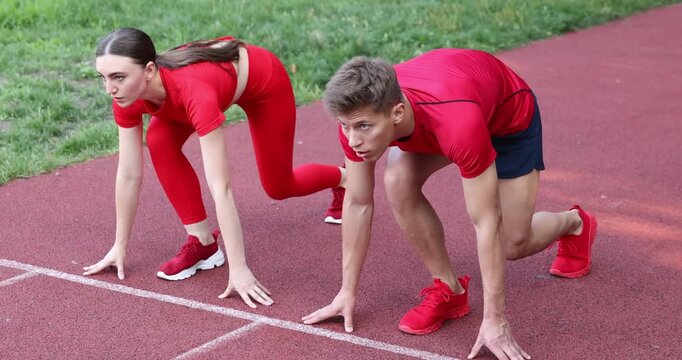 Athletes getting into start position and running at stadium