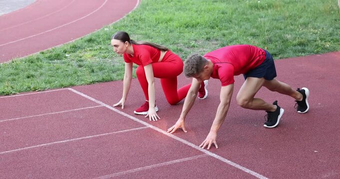 Athletes getting into start position and running at stadium