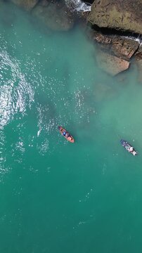 Vista a&eacute;rea de duas pessoas praticando stand up paddle em &aacute;gua turquesa cristalina perto de forma&ccedil;&otilde;es rochosas, aventura aqu&aacute;tica durante viagem a Alagoas