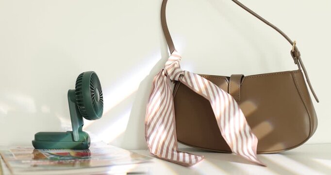 Mini fan, magazines and bag on white table