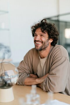 Smiling casual man at desk with globe and glass bottle for modern office lifestyle portrait and workspace banner design