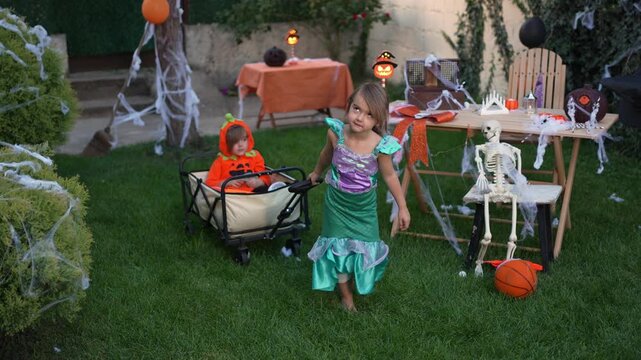 Slow motion of kids in halloween costumes playing together during a party in a decorated backyard