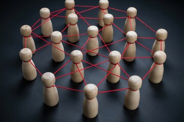 Obraz premium Wooden figures connected by red strings representing a social network or team collaboration
